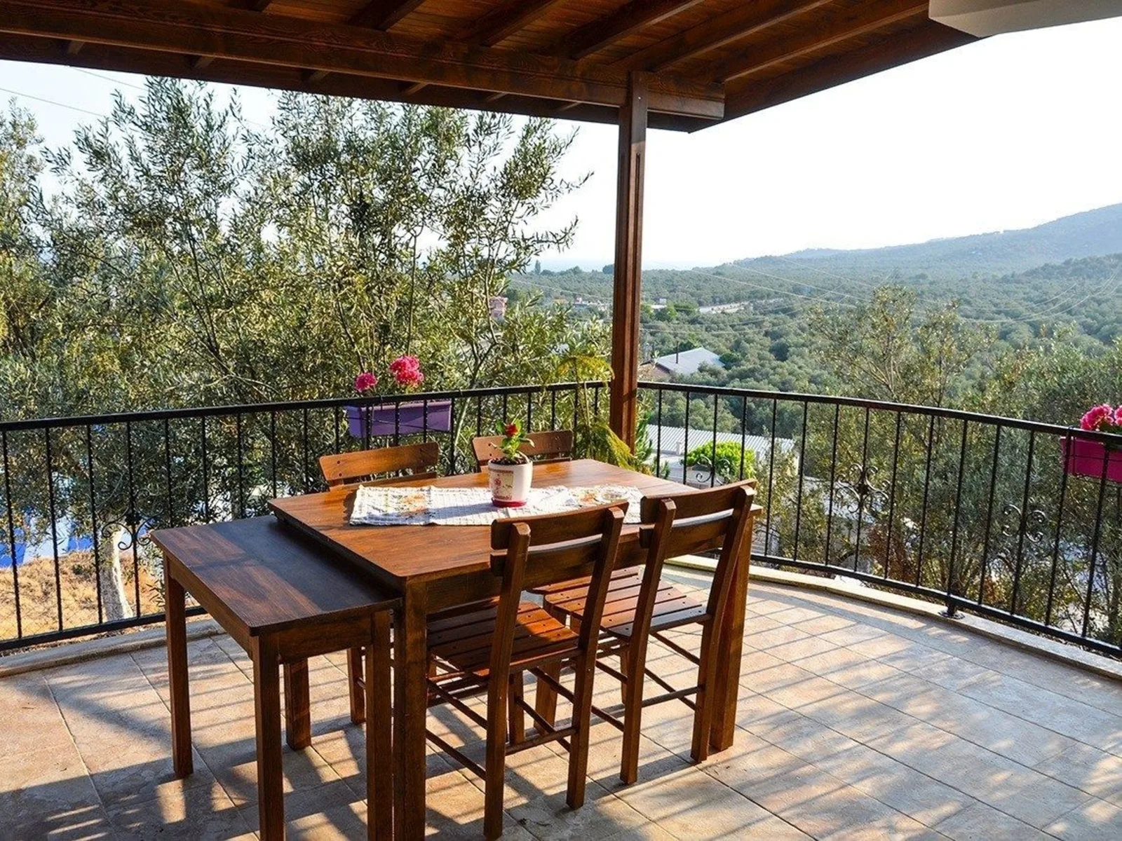 A room balcony with a wooden table, the olive grove and the hills