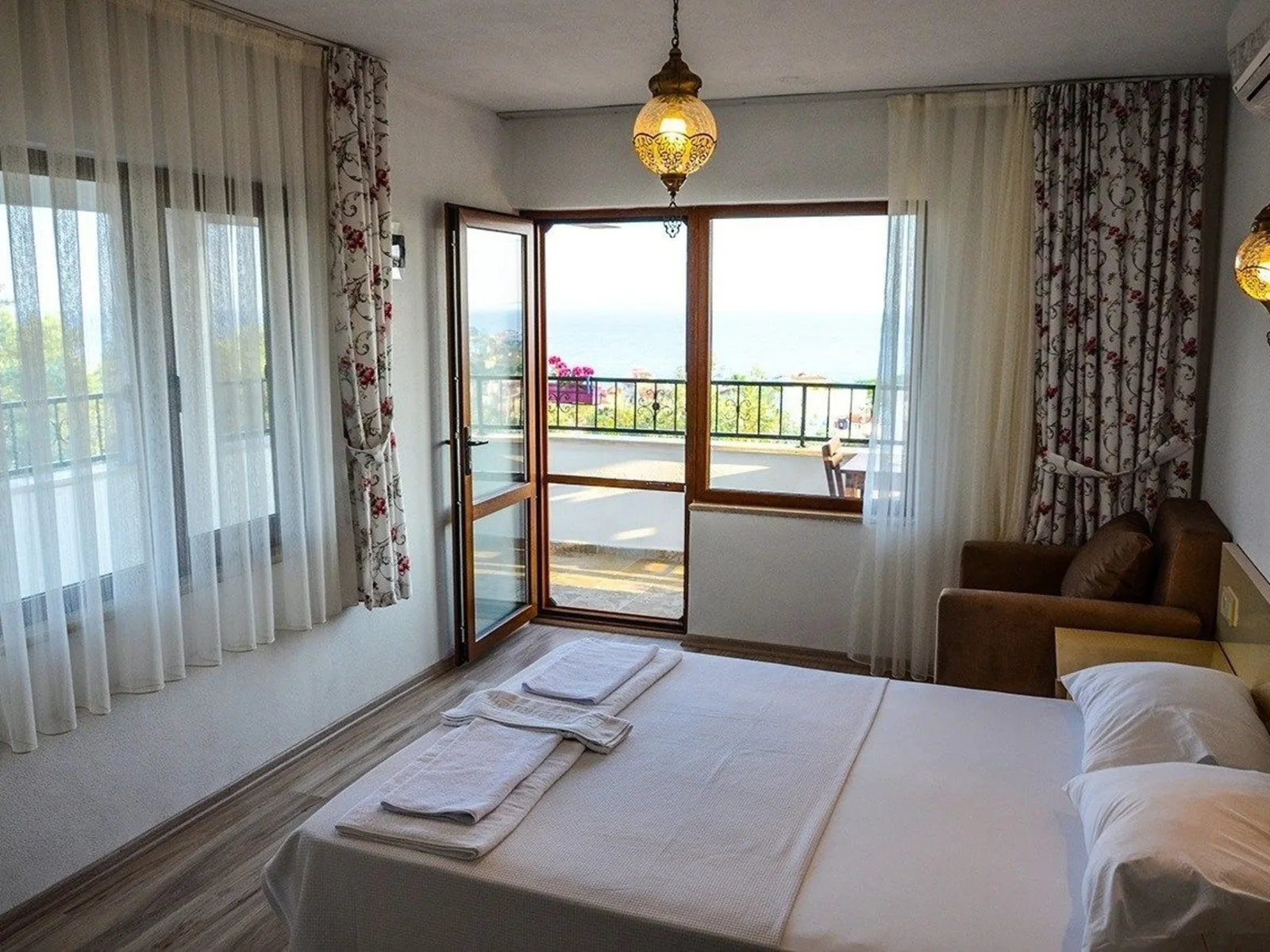 A sea-view room: balcony door open, an armchair and a double bed