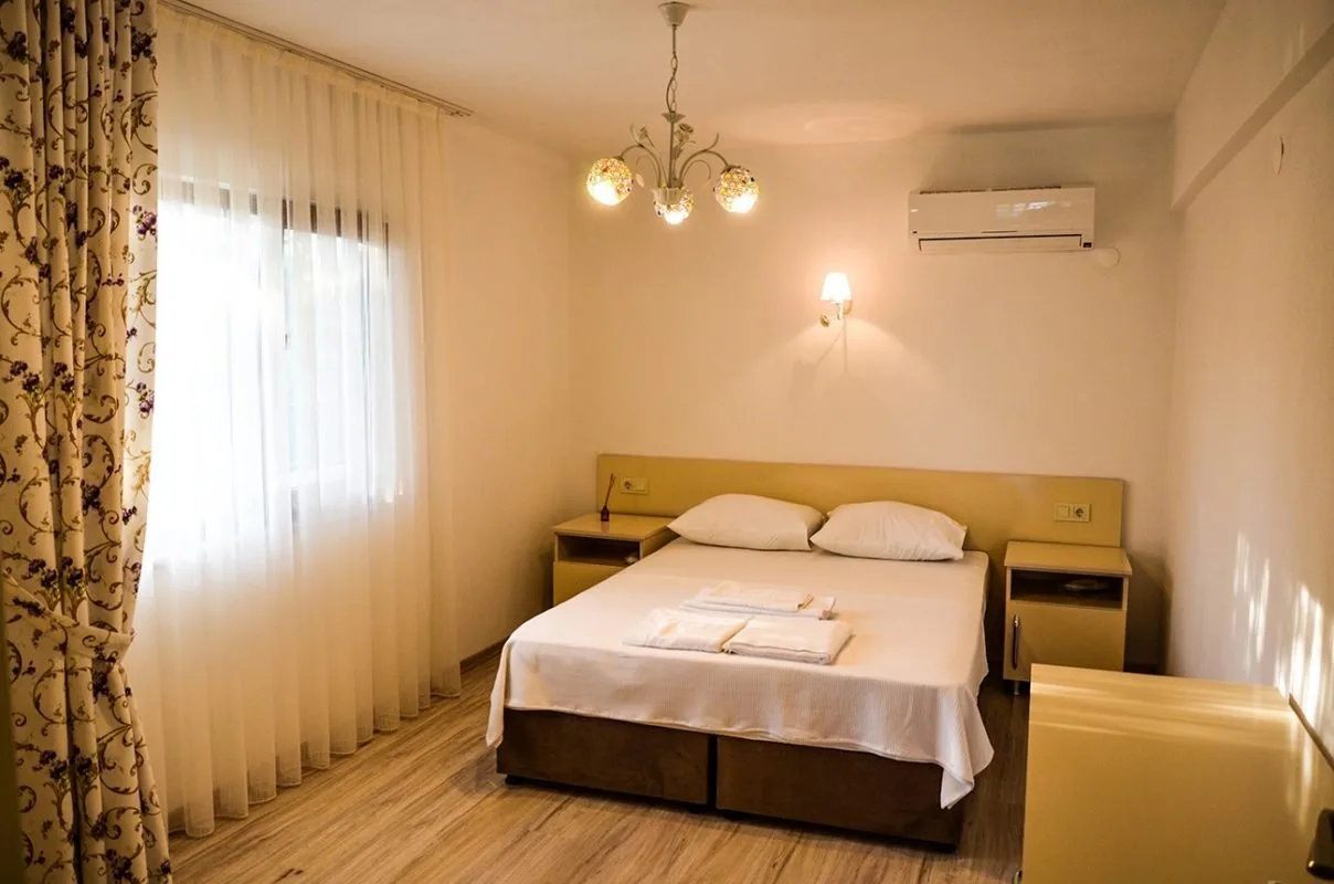 A twin room with a chandelier, air conditioning and curtained window