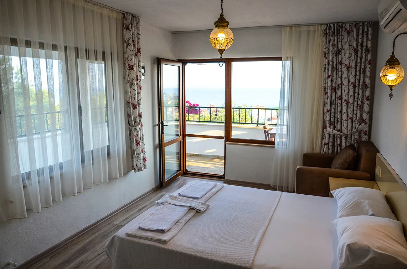 A room with its balcony door open, looking out over the Gulf of Edremit